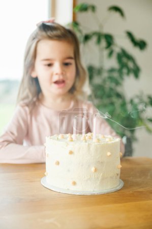 Photo for A childs delight at a birthday party, with a freshly blown-out candle on the cake, smoke rising. Little girl 3 years old wearing pink top, sitting at table with a birthday cake. celebration concept - Royalty Free Image