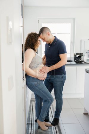 Foto de Foto vertical de una pareja embarazada romántica en casa manos en el vientre. embarazo, familia, concepto de personas - Imagen libre de derechos