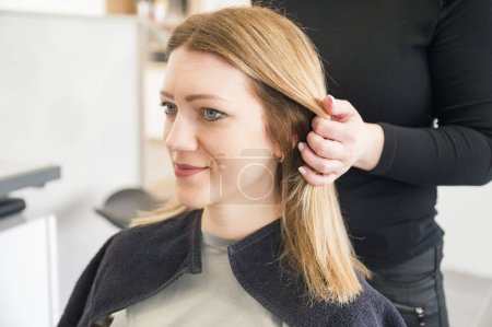 Téléchargez les photos : Professionnel jeune coiffeur coupe et vérification jeune belle femme caucasienne dans le salon de beauté moderne. - en image libre de droit