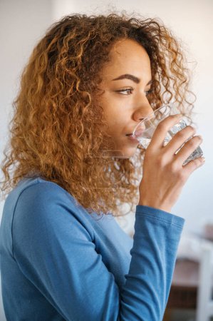 Photo for Young black woman drinking water from glas at home - Royalty Free Image