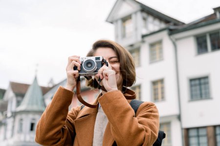 Foto de Retrato de una joven feliz tomando una foto con una cámara analógica visitando una ciudad - Imagen libre de derechos