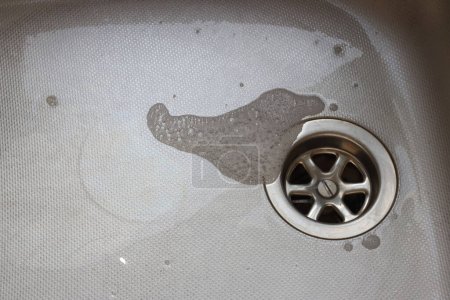 Sink plughole with soap bubbles around it. 