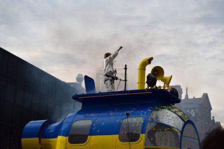 Téléchargez les photos : Liverpool, Merseyside, Royaume-Uni - 5 mai 2023 : Concours Eurovision de la chanson 2023, le Blue and Yellow Submarine Parade donne le coup d'envoi de la fête à Liverpool pour le lancement du hub des fans de l'EuroVillage. Homme dansant sur grand char de parade. - en image libre de droit