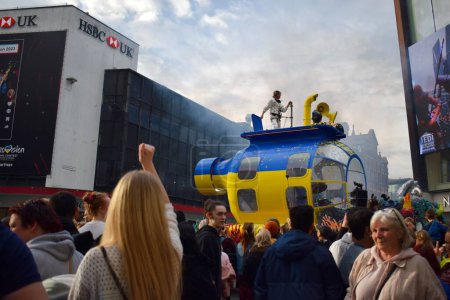 Photo for Liverpool, Merseyside, United Kingdom - May 5 2023: Eurovision Song Contest 2023, the Blue and Yellow Submarine Parade kicks off the party in Liverpool for the launch of EuroVillage fan hub. Man dancing on big parade float. - Royalty Free Image