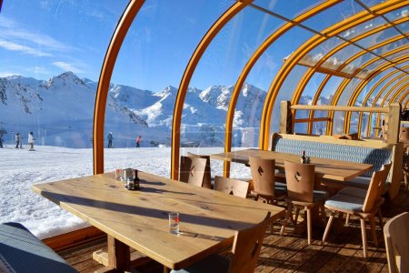 Foto de Hochgurgl, Tirol, Austria - 25 de enero de 2023: Hermosa vista soleada a la montaña nevada desde el interior de un restaurante alpino austriaco en una concurrida estación de esquí - Imagen libre de derechos