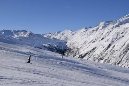 Skiers and snowboarders in Hochgurgl ski resort, backdropped by the Otztal valley and the snow capped alpine mountains in Tyrol, Austria on a beautiful sunny day, perfect conditions for winter sports.