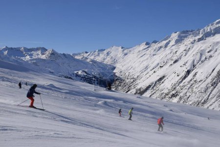 Foto de Esquiadores y snowboarders en la estación de esquí de Hochgurgl, telón de fondo por el valle de Otztal y las montañas alpinas cubiertas de nieve en Tirol, Austria en un hermoso día soleado, condiciones perfectas para los deportes de invierno. - Imagen libre de derechos