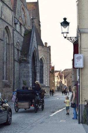Photo for Bruges, Belgium - June 8 2023: Horse drawn carriage pulling tourists through the historic streets of Bruges in the summer. Medieval tourist destination: Bruges the capital of West Flanders in Belgium. - Royalty Free Image
