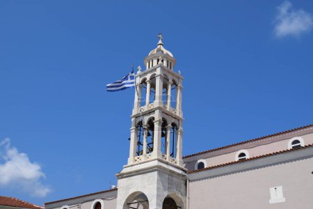 A Greek flag waving in the wind from the bell tower of a Greek Orthodox church (Cathedral of the Three Hierarchs) in Skiathos town, Greece.