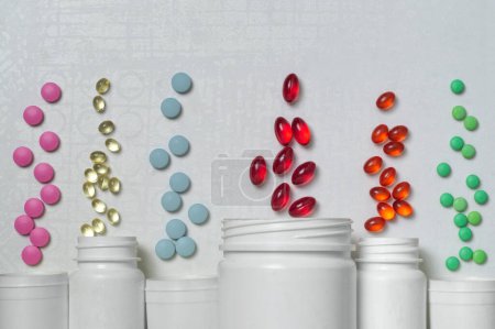 Pilules et capsules multicolores avec des médicaments ou des vitamines volent à partir de cinq pots en plastique blanc