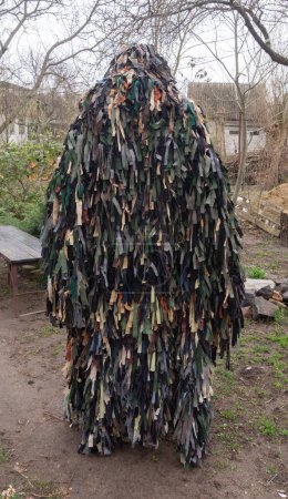 Man in a kikimora camouflage net woven by volunteers from scraps of fabric. Russian-Ukrainian war
