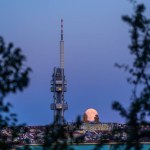 The rising full moon above Prague cityscape with Zizkov TV tower.
