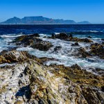 Table mountain in Cape Town from a distance Robben Island. Rocky cliffs in the foreground.