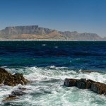 Table mountain in Cape Town from a distance Robben Island. Rocky cliffs in the foreground.