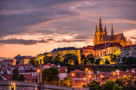 Foto de Castillo de Praga y Manesuv la mayoría (puente de Manes) sobre el río Moldava en Praga en el atardecer cielo rojo. - Imagen libre de derechos