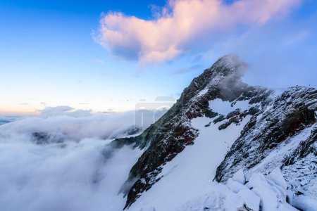 Téléchargez les photos : Un nuage rose au-dessus de la plus haute montagne autrichienne Grossglockner dans le parc national du Haut Tauern à l'aube. - en image libre de droit