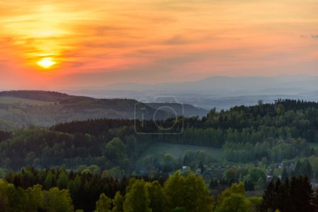 Foto de Una puesta de sol naranja sobre las montañas Orlicke hory y Krkonose en la distancia. - Imagen libre de derechos