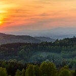 An orange sunset over Orlicke hory and Krkonose mountains in the distance. 