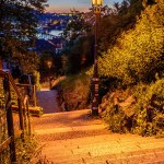 Shining lamps on the Vysehrad stairs with Prague castle and Vltava river in the background. in an orange sunset.