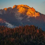 An orange mountain peak of Sierra Nevada mountains viewed from Moro Rock in Sequoia National Park during sunset.