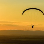 A man paragliding during the sunset. 
