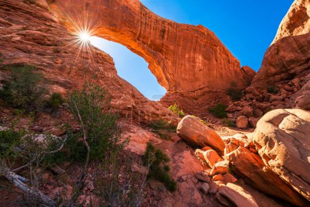 The lens flare sun star lighting through the North Window Arch in the Arches National Park in the Moab, Utah, USA.