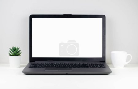 Foto de Portátil con pantalla en blanco en escritorio blanco con taza de café y planta casera. Concepto de oficina en casa y espacio de trabajo - Imagen libre de derechos