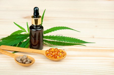 Foto de Frasco de aceite de CBD, hojas medicinales de cannabis y cápsulas y tabletas de CBD sobre mesa de madera - Imagen libre de derechos