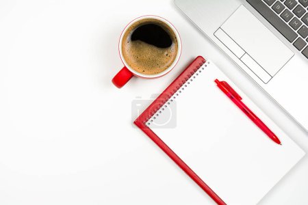 Foto de Taza de café rojo con bloc de notas rojo y pluma, teclado portátil sobre fondo blanco. Vista superior con espacio de copia - Imagen libre de derechos