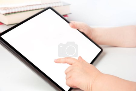 Foto de Las manos del niño sosteniendo la tableta digital y tocando la pantalla en blanco, concepto de aprendizaje electrónico - Imagen libre de derechos