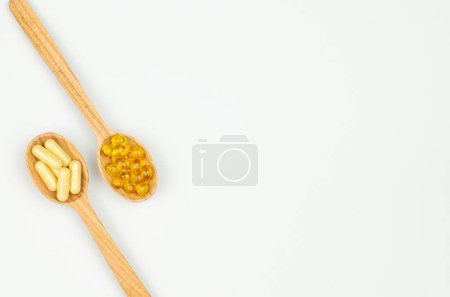 Foto de Cápsulas de suplemento dietético en cucharas de madera sobre fondo blanco, composición del borde con espacio para copiar - Imagen libre de derechos