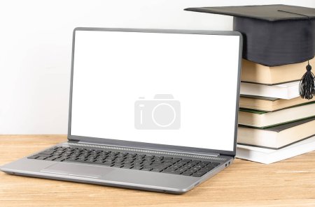 Foto de Laptop con pantalla en blanco cerca de la pila de libro con sombrero de graduación. E-learning y concepto de graduación en línea - Imagen libre de derechos