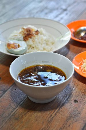 Téléchargez les photos : Rawon authentique de Java Est, Indonésie. Cuisine traditionnelle indonésienne. bœuf cuit à la sauce noire, servi avec oeuf de canard salé, germes de haricots, craquelins et sauce chili. - en image libre de droit