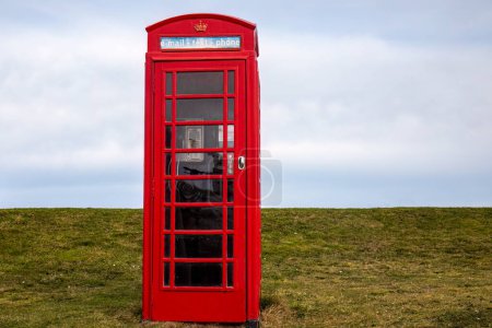 Téléchargez les photos : Cabine téléphonique rouge dans une ville balnéaire écossaise au bord de la plage - en image libre de droit