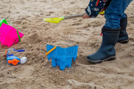 Foto de Niños pequeños jugando con un cubo y pala en la playa construyendo castillos de arena - Imagen libre de derechos
