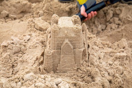Téléchargez les photos : La construction d'un château de sable pour enfants sur la plage en vacances - en image libre de droit