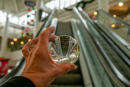 Foto de Fotografía bola de vidrio en mano humana fotografiando escaleras mecánicas vacías, artístico, arte - Imagen libre de derechos