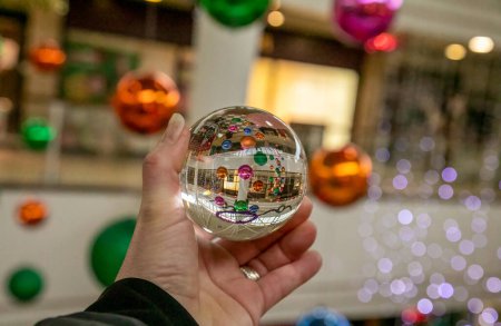 Photo for Photography glass ball in human hand taking photographs of Christmas baubles in a shopping mall - Royalty Free Image