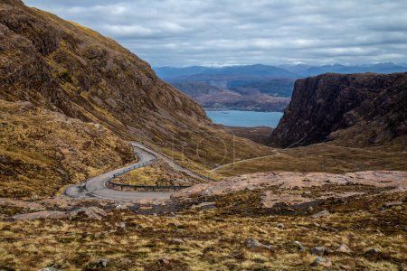Foto de Hermoso paisaje de montaña con larga y sinuosa carretera de una sola pista en la ruta NC500, Bealach na Ba, Applecross, Escocia, ruta turística - Imagen libre de derechos