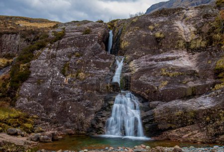 Photo for Mountain river with a waterfall in a sunny day in Glencoe, Scotland.  Iconic Scottish waterfall.  Attracts tourists on holiday, tourism and vacations to Scotland with such beautiful landscape and scenery - Royalty Free Image