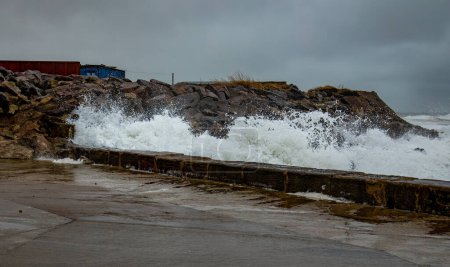 Olas muy altas durante una tormenta de marea alta que rompe una pared del puerto