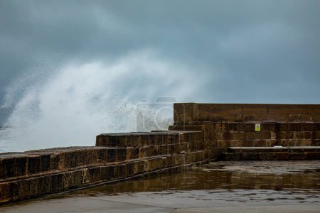 Sehr hohe Wellen während eines Sturmtiefs, das eine Hafenmauer durchbricht