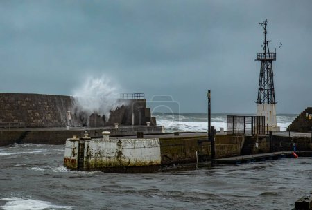 Sehr hohe Wellen während eines Sturmtiefs, das eine Hafenmauer durchbricht