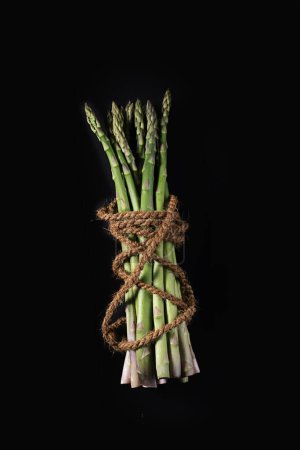 Asparagus on blue dish on black background with cocos rope