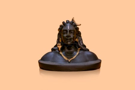 Téléchargez les photos : Version miniature de l'idole Adiyogi Shiva assise sur fond orange réfléchi - en image libre de droit