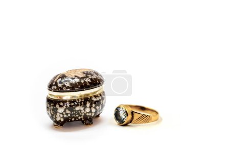 Photo for Small black and white ceramic jewelry box with a gold ring on the neck and a gold ring with a diamond on it place on white background - Royalty Free Image
