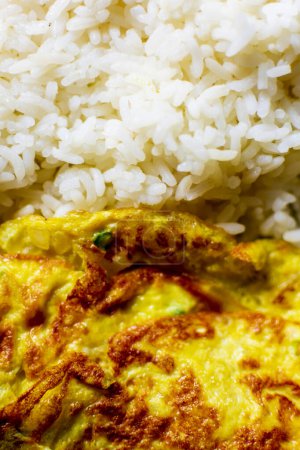 Foto de Tortilla de huevo plegada mantenida en el arroz caliente en un plato de comedor hábito de comida india saludable - Imagen libre de derechos