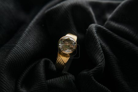 Téléchargez les photos : Bague en or avec pierres zircon posée sur tissu velours noir, photographie d'ambiance - en image libre de droit