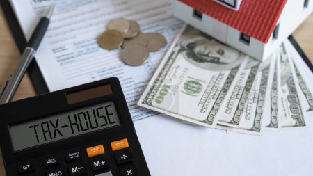 Tax house on calculator and Miniature house with money on tax papers. The concept of paying tax for housing and property. Debt payment. Property taxes. Tax house concept. 