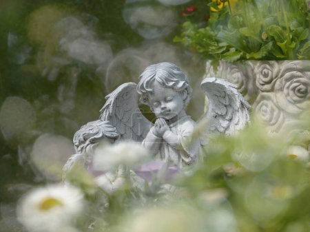 Engel mit Flügeln und weißem Herzen im Park in Prag, kleiner Engel mit Flügeln gegen das Licht